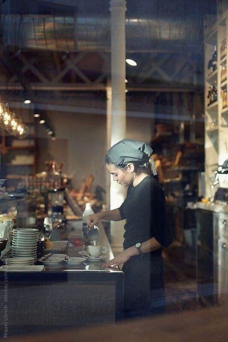 A hospitality professional working during service in a warm-lit cafe